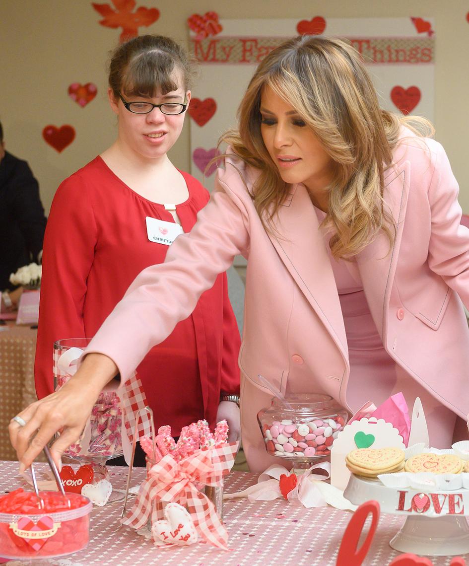 Using tongs, First Lady, alongside an inn resident, chooses red candies for a gift box