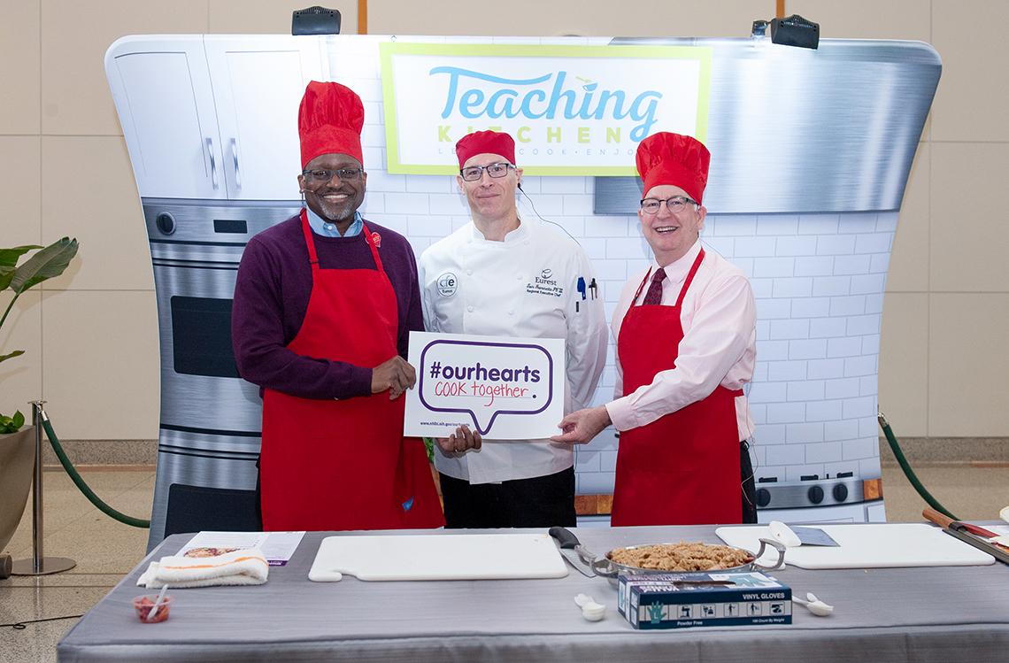 Gibbons, chef Fiammetta and Goff hold sign that says #ourhearts cook together