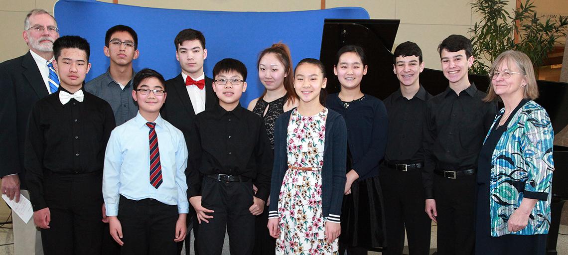 Group of youngsters smiling into camera, flanked by an adult on each side