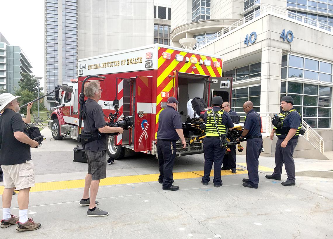 NIH first responders are filmed as they load ambulance during drill. 