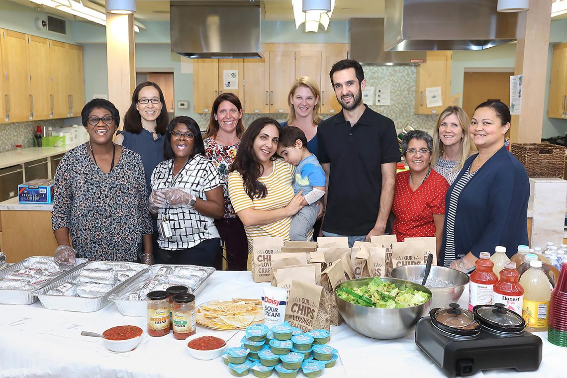 NIDCR employees and inn family smile behind buffet table.
