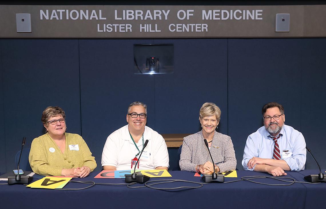 Four employees sit at a table facing the camera