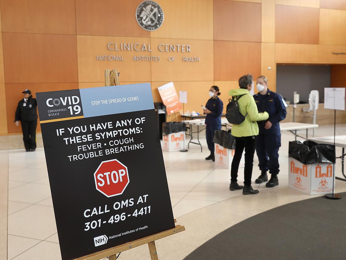 View of Clinical Center lobby with uniformed personnel in face masks waiting to screen entrants.