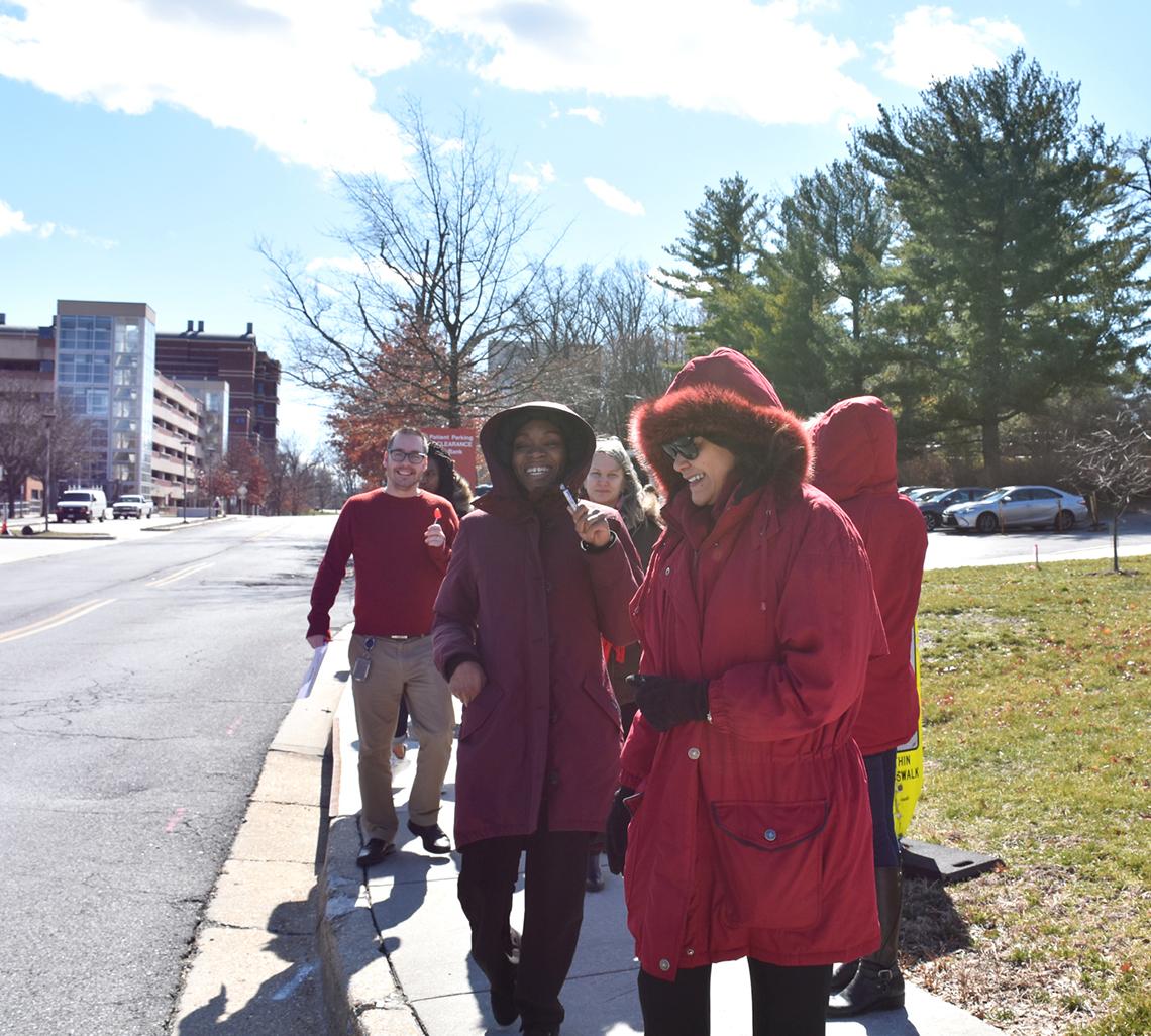 Several people walk across campus while wearing red.