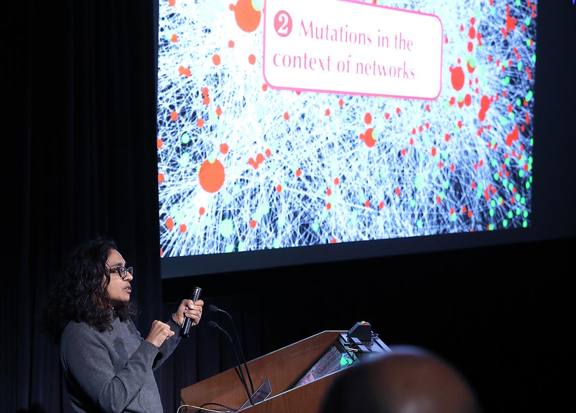 Singh speaks in front of a slide