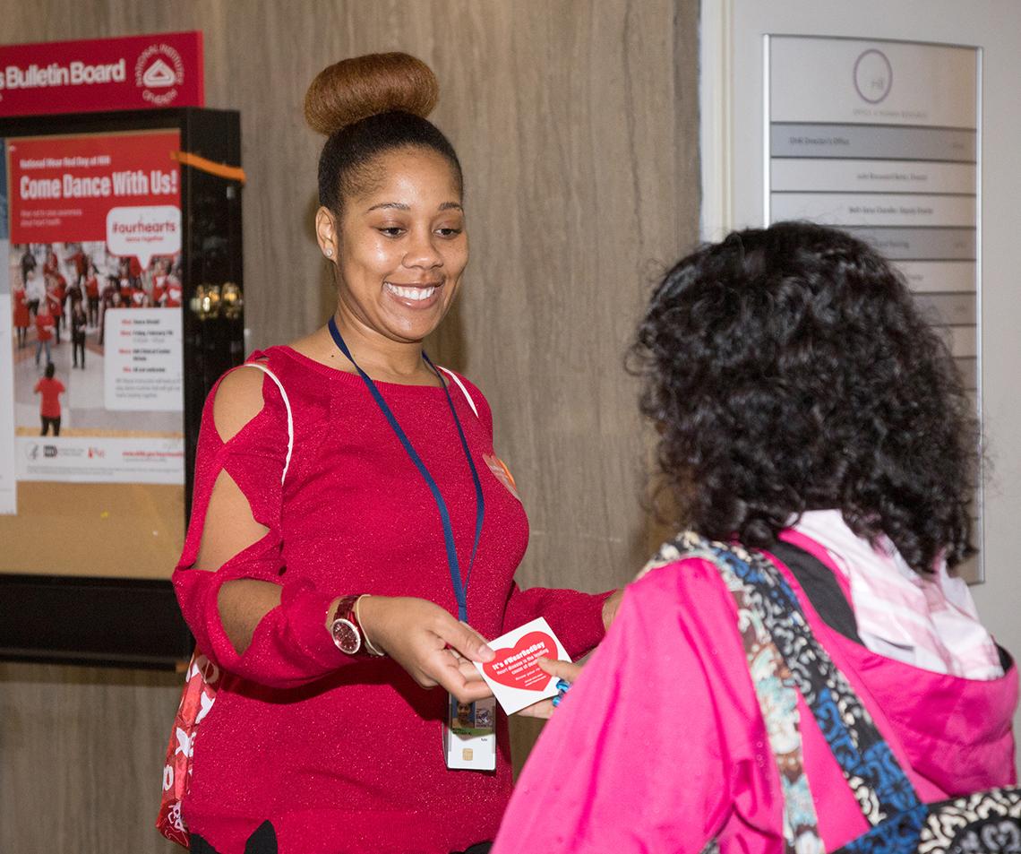 Woman hands heart-shaped sticker to employee.