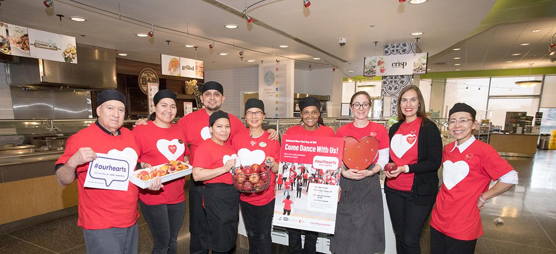 Group of people dressed in red, holding red food and signs.