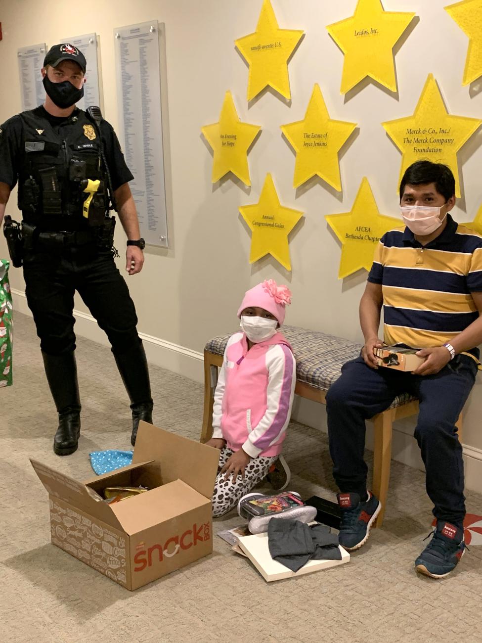 Police officer watches a young patient open presents