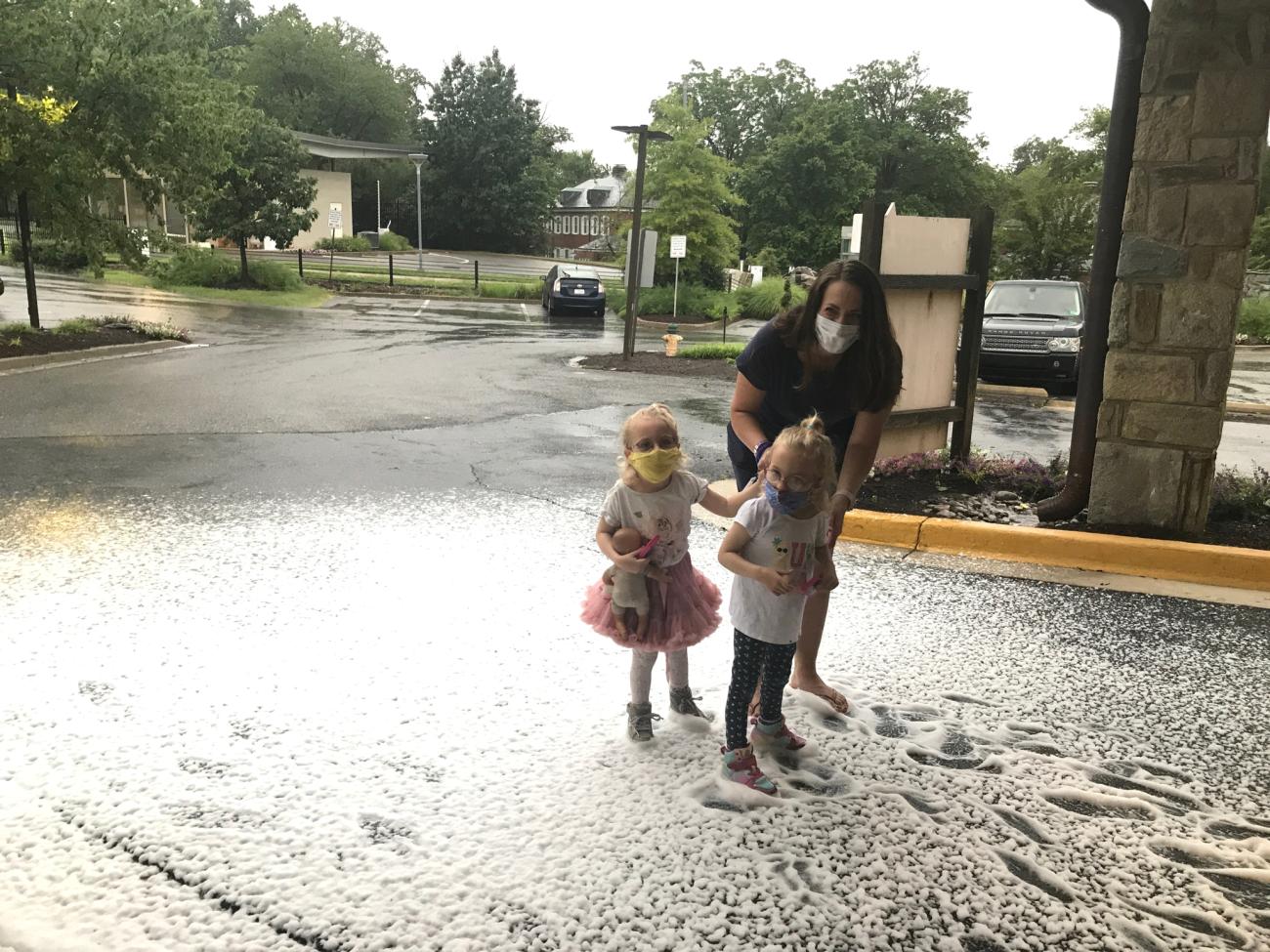 Twin toddler girls play in the snow with their mom outside the Children's Inn.