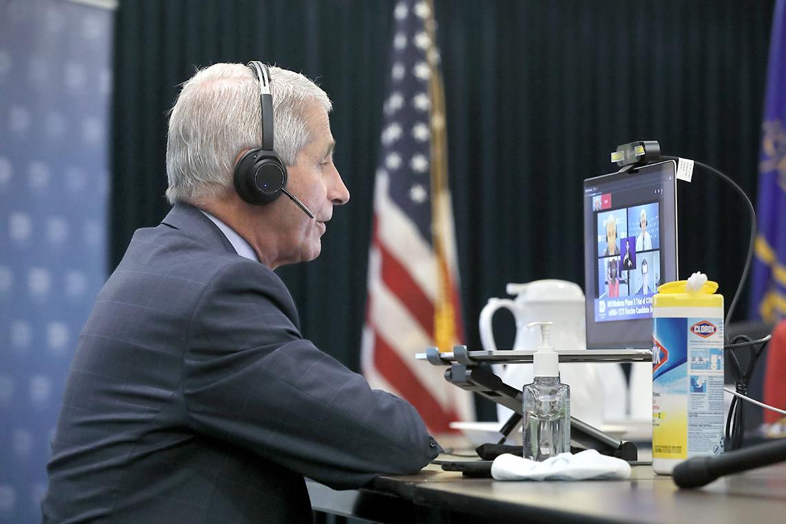 Fauci wearing headset sits in front of computer screen