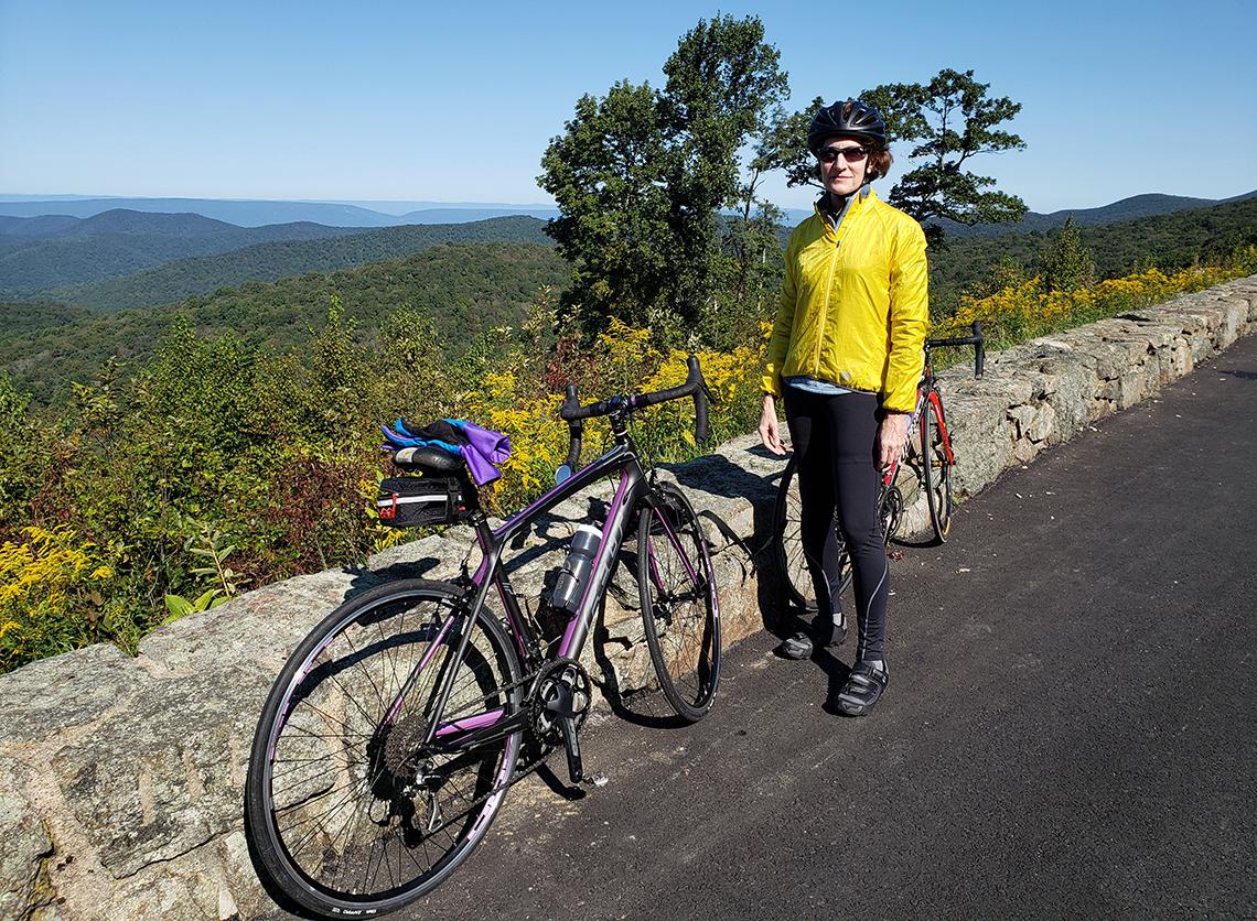 Marill next to her bike surrounded by the hills and foliage of Skyline Drive in Virginia
