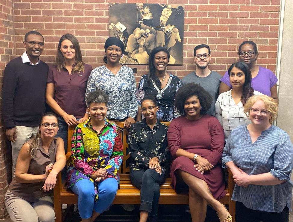 Dr. Paule Joseph, surrounded by 11 smiling colleagues.