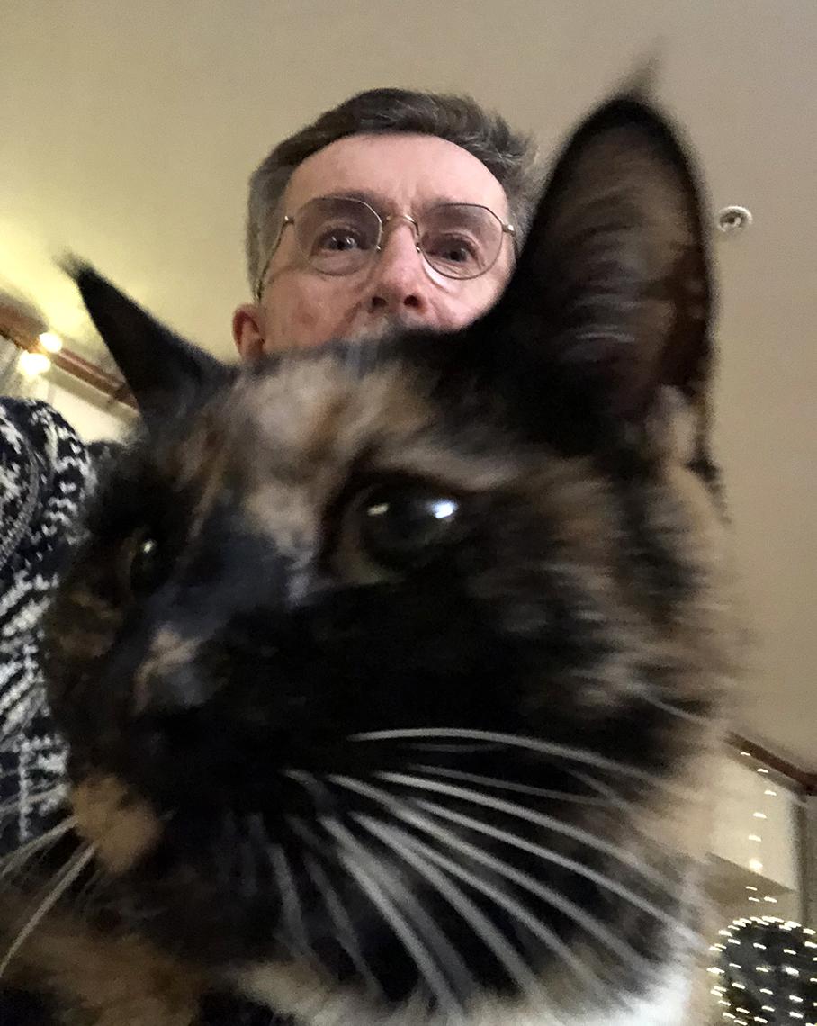 Peter Lyster peers over his cat.