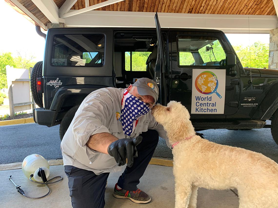 Andrés in mask meets dog.