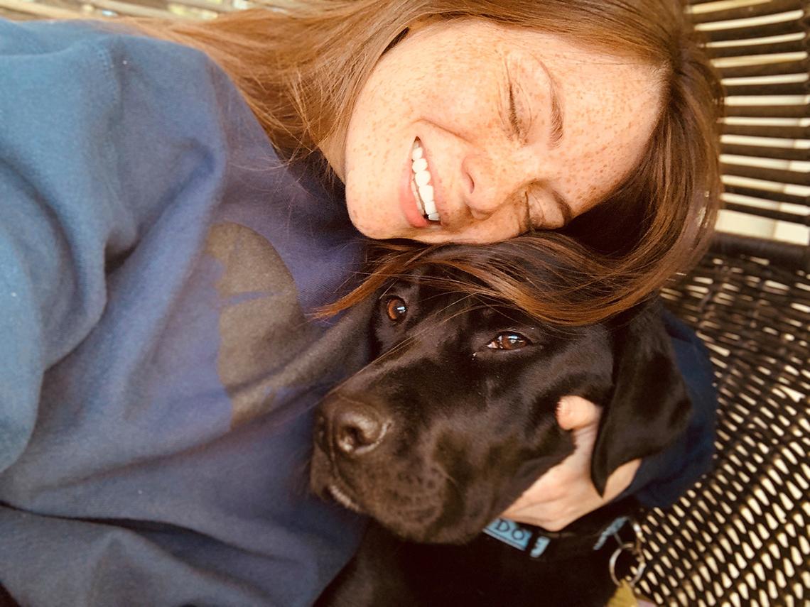 Woman cuddles pup.
