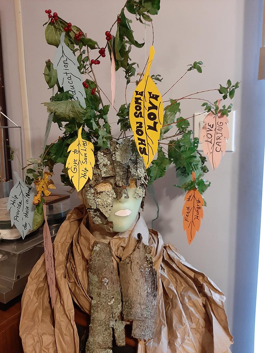 Mask called the Wishing Tree features branches with green leaves and handwritten tags