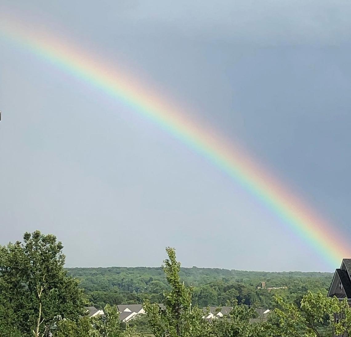 A huge rainbow spans the highway.