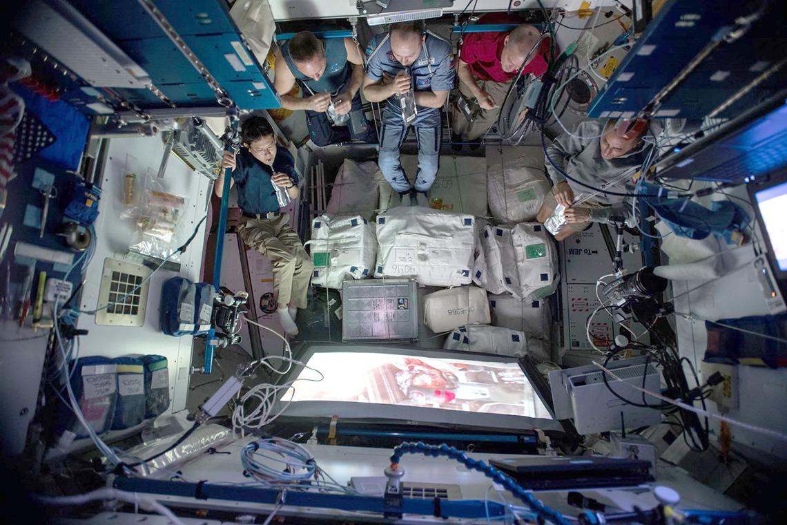Overhead view of astronauts watching a movie aboard the ISS