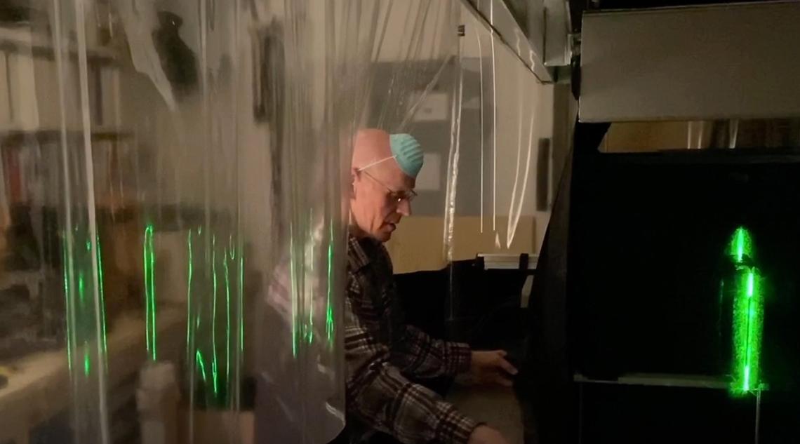 A researcher behind plastic sheeting runs an experiment in the lab.