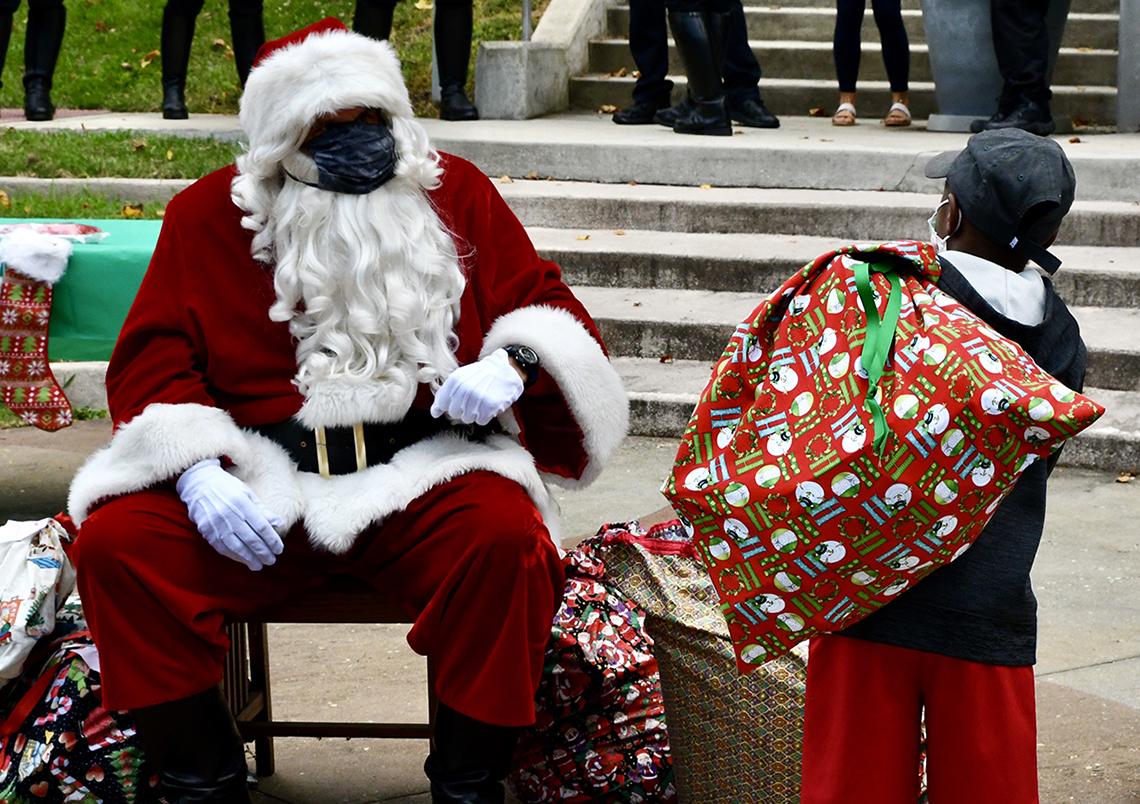 A little boy walks over to a seated Santa