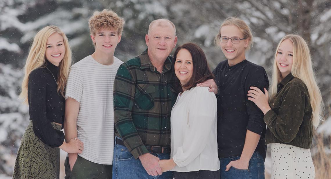 A wintertime photo of the Schmaedeke family, posing outside, surrounded by snow flurries
