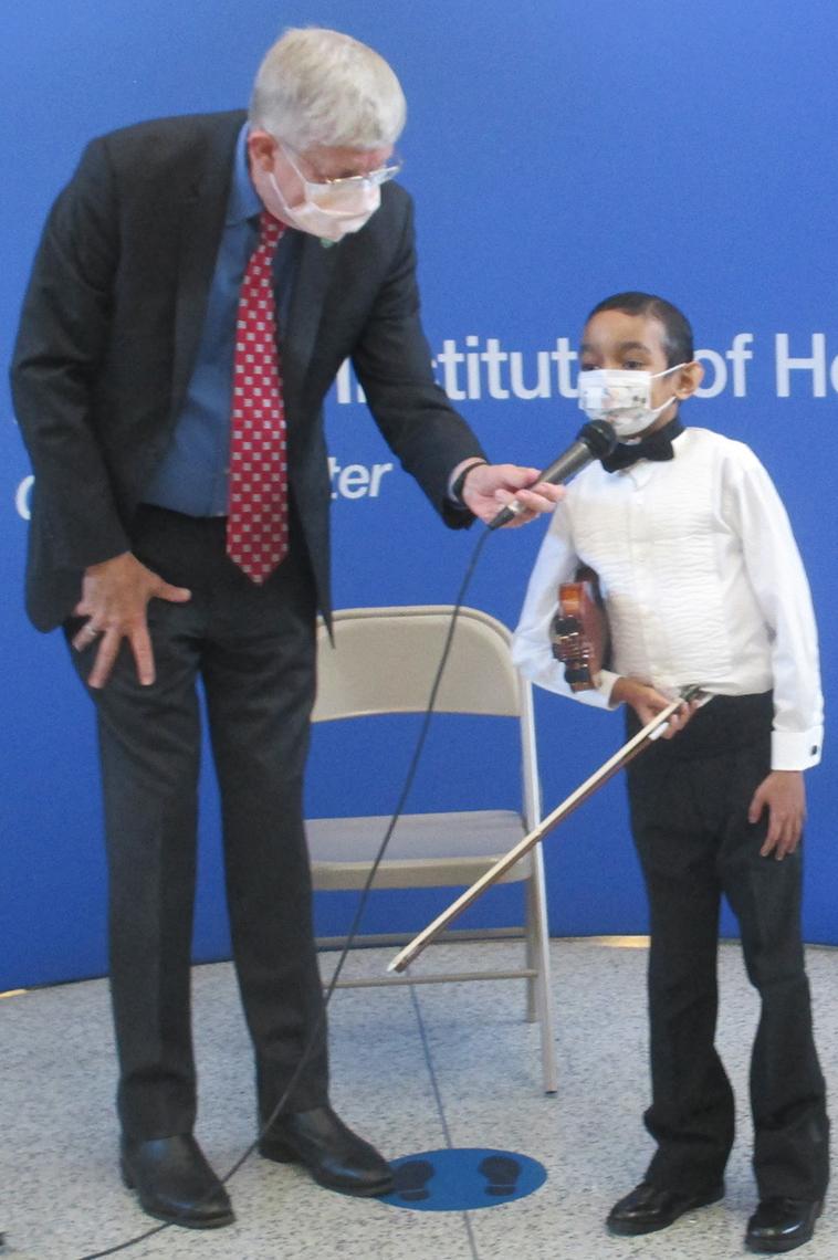 Collins stands, bending down to hold the microphone as Sant speaks into it.