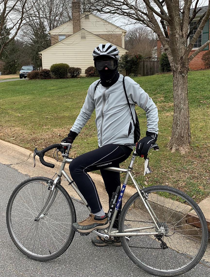 Murphy, dressed in warm clothes and a balaklava, sits on his bicycle outside his home.