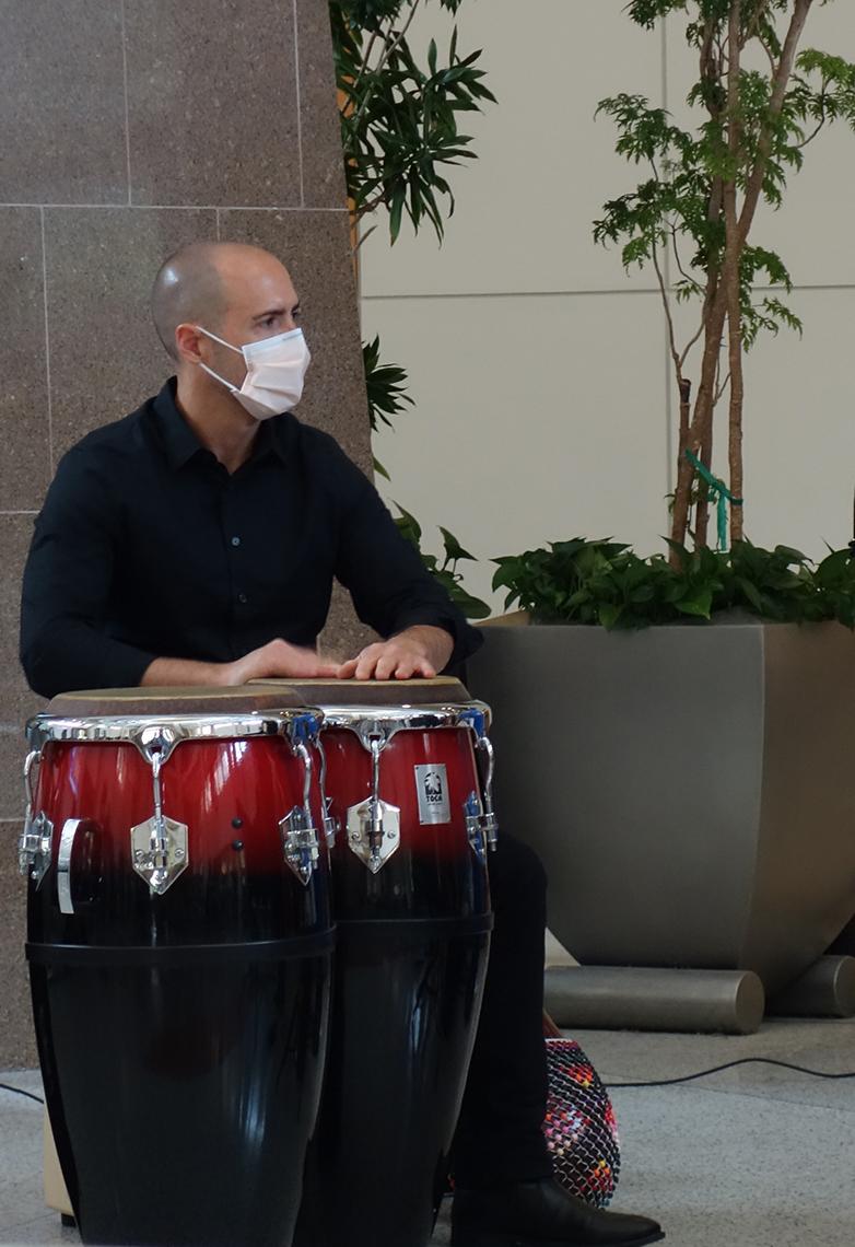 A man rests his hands on conga drums.