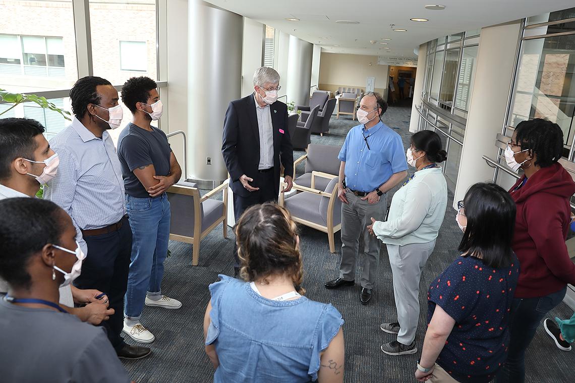 Collins stands in a circle of staff in the CC 5th floor atrium.
