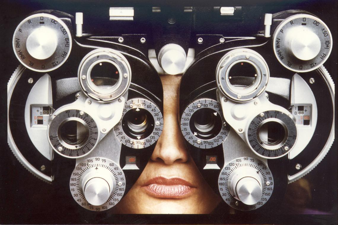 Huss' face sits behind a phoropter, an instrument commonly used by eye care professionals during an eye examination, and contains different lenses used for refraction of the eye during sight testing.
