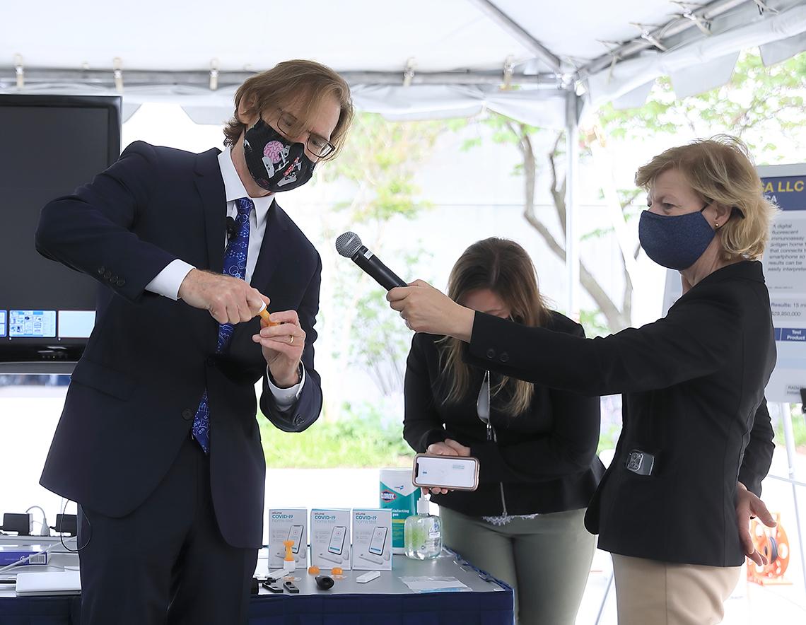 Tromberg shows off a product while Baldwin holds a mic.