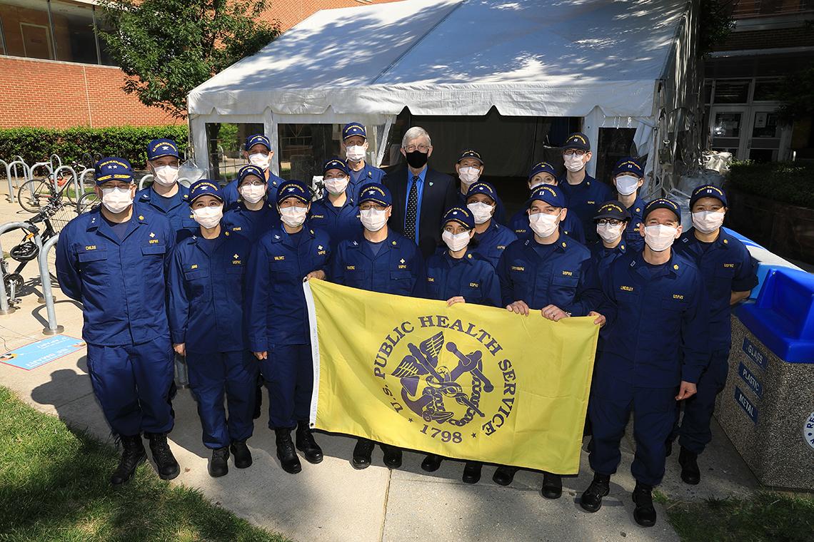 A group PHS members get their photo taken with Collins. Three members in the front hold the PHS flag.