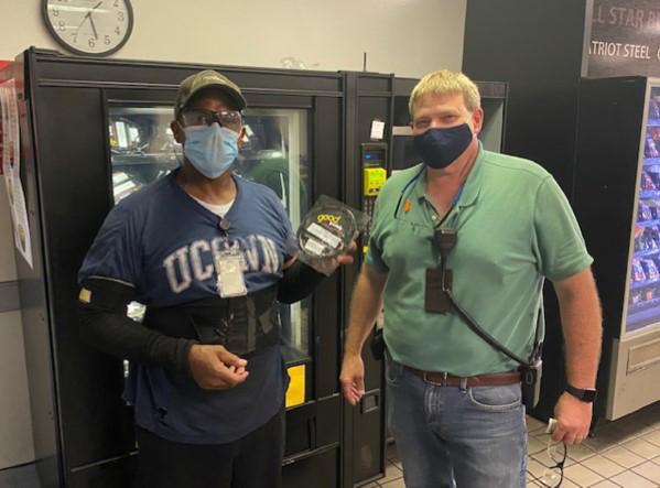 Two employees stand in front of a vending machine