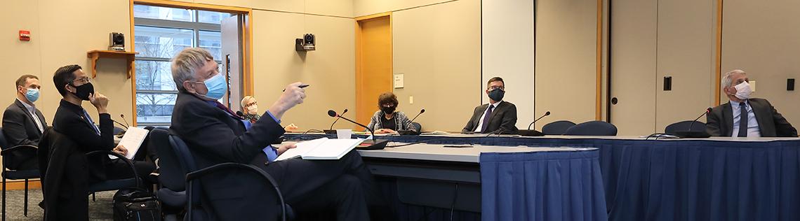 NIH vaccine researchers sitting around a long conference table talking with Lander