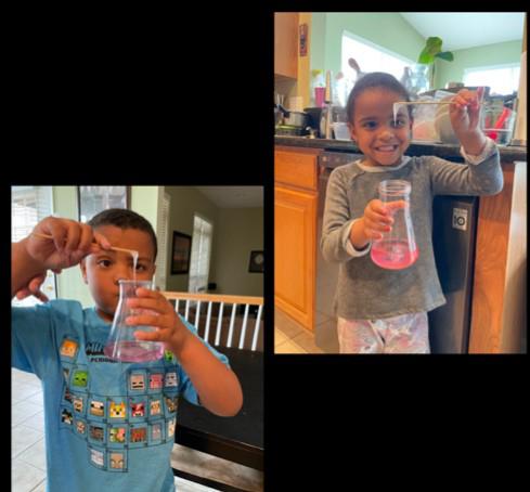 Isaac and Gabriella hold up a beaker with strawberry DNA 