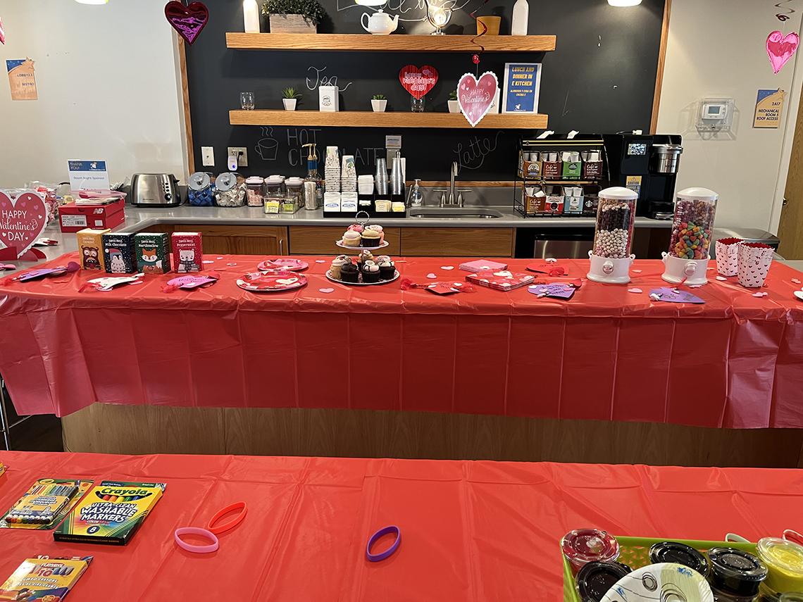 Crayons and markers sit on a table with a red table cloth