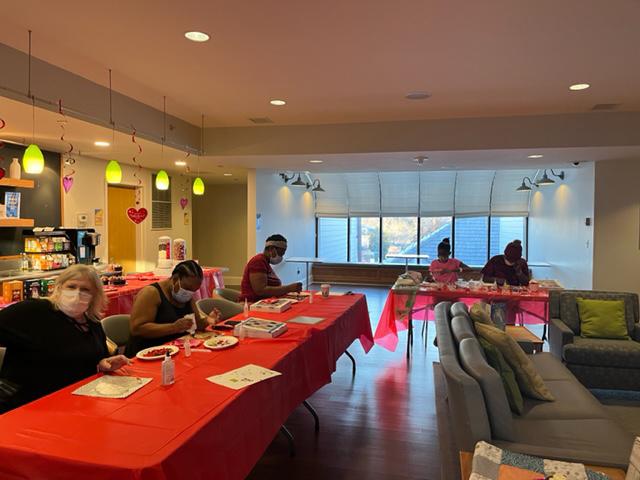 Inn resdients sit at a table while doing arts and crafts