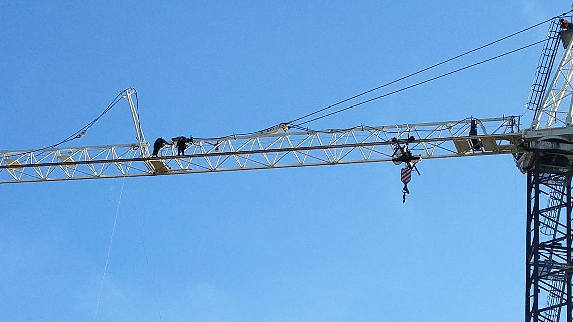 Two tiny figures high up on a large crane