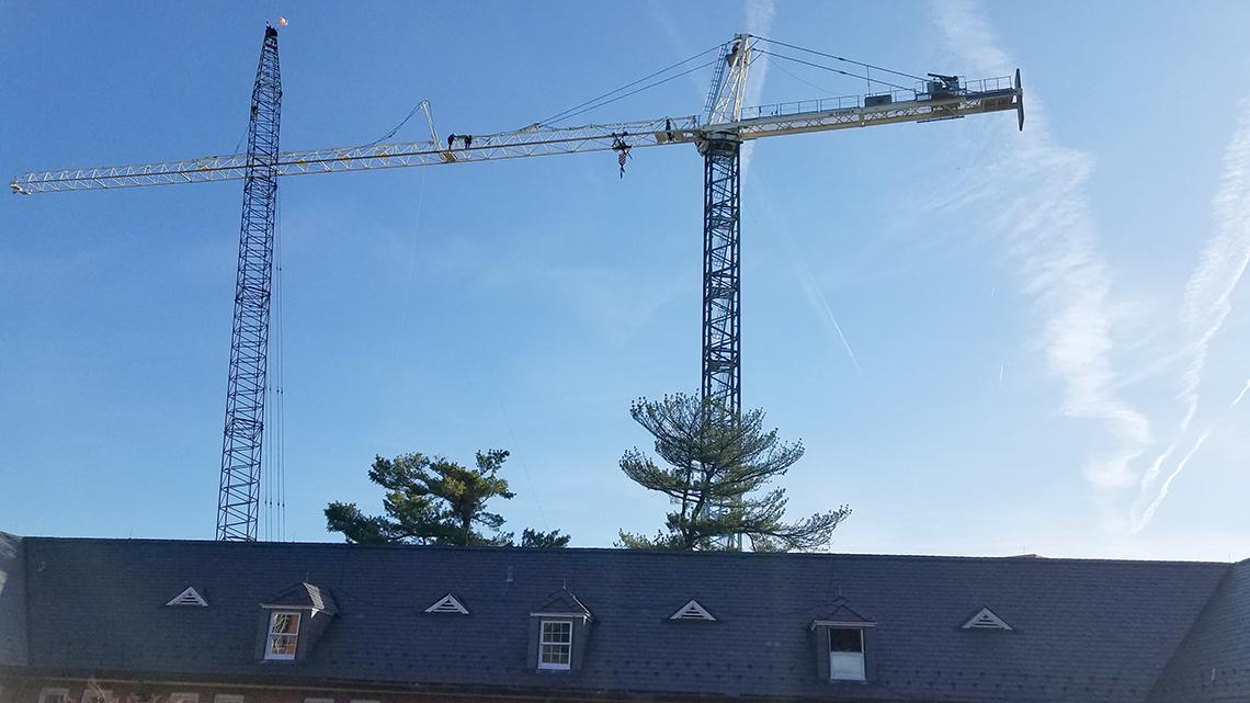 Two tiny figures high up on a large crane
