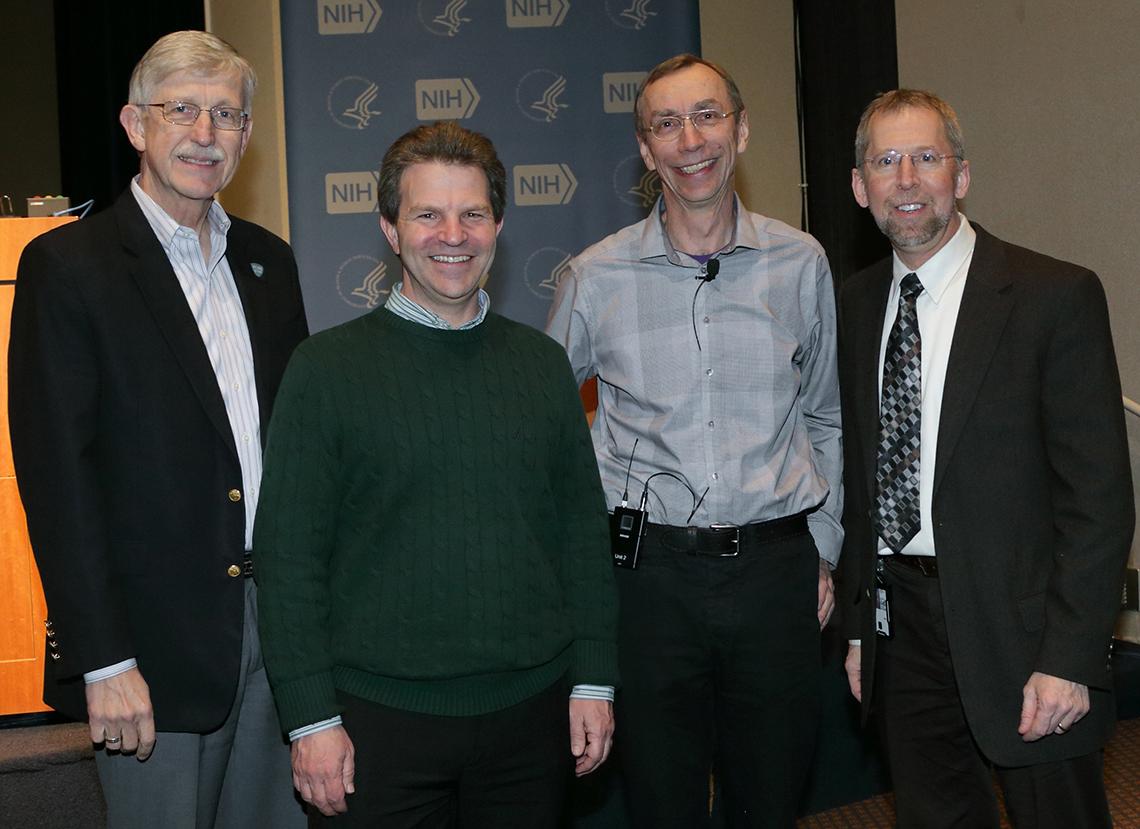 Collins, Green, Pääbo and Mullikin stand together in front of a podium