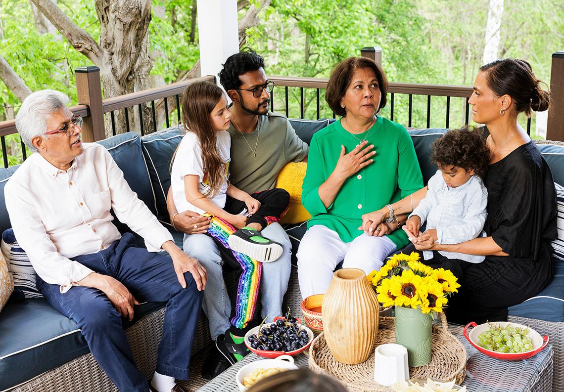 The Ambudkar family relaxes on a wicker sectional couch on their new deck