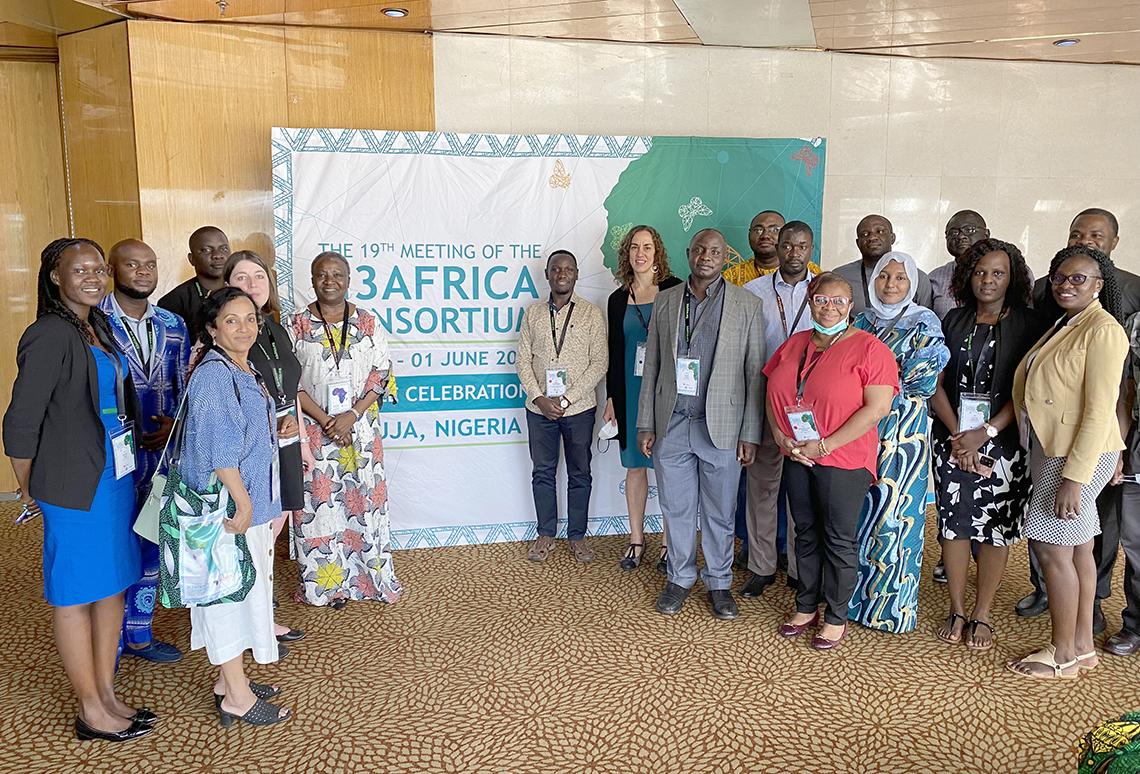 A group of researchers gather on either side of green and white H3Africa Consortium backdrop.