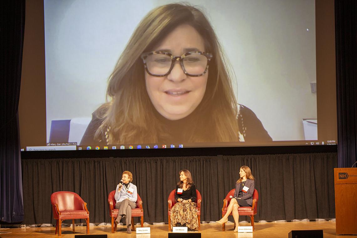 Gan projected on a big screen above the two seated panelists and moderator in Kirschstein Auditorium.