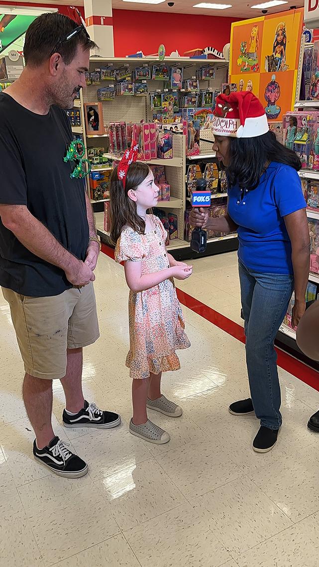 A TV reporter interviews a girl and her father in a Target