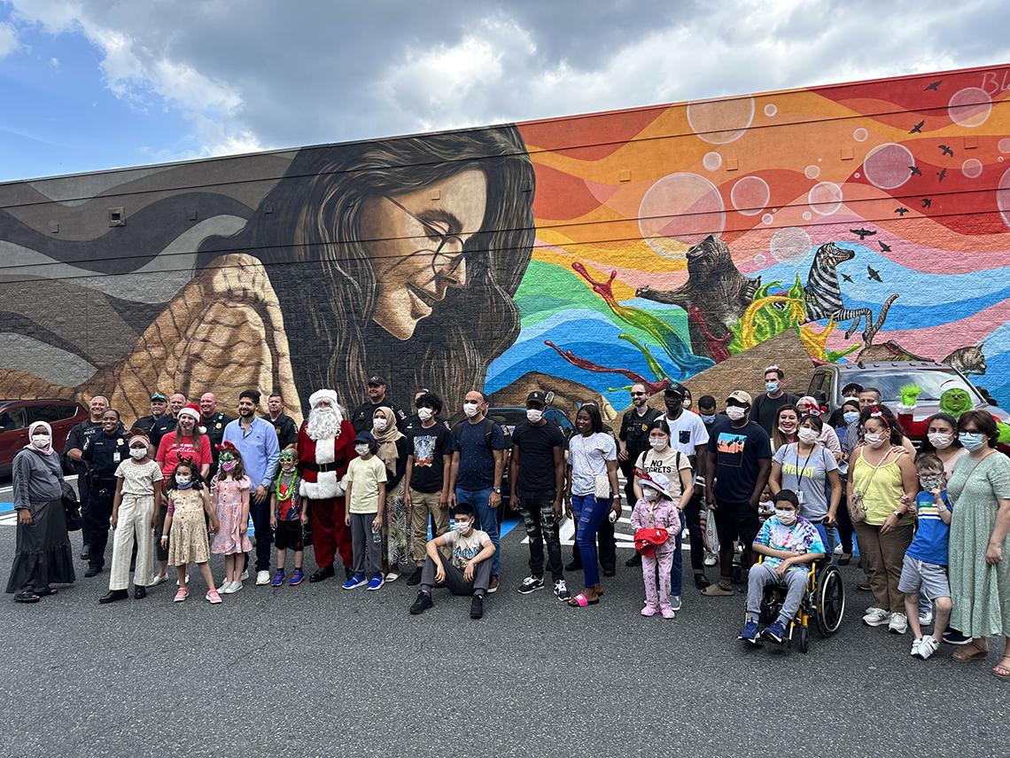 A group photo in front of a large, colorful mural that illustrates the love of books and reading