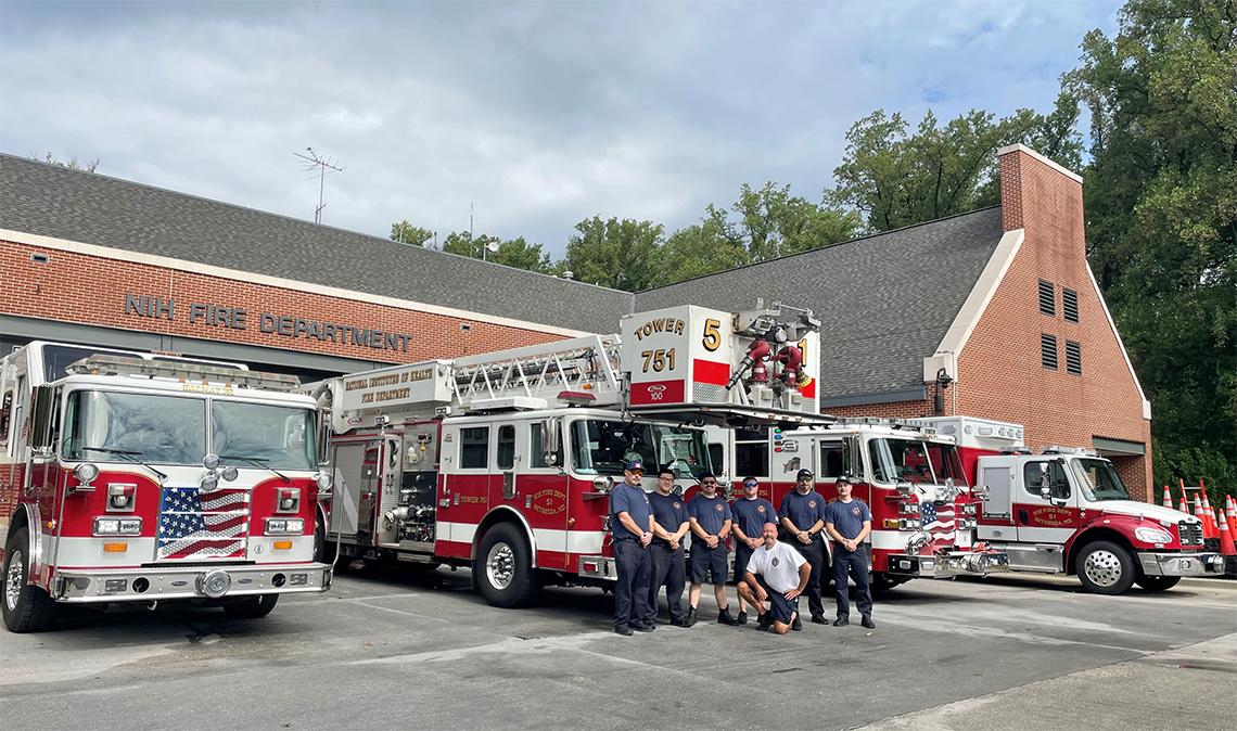 Fire fighters stand in front of fire truck outside the NIHFD apparatus bay.