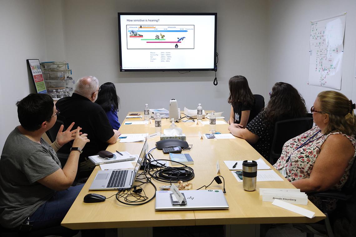 A table of viewers watch Bernhard's slide show presentation.