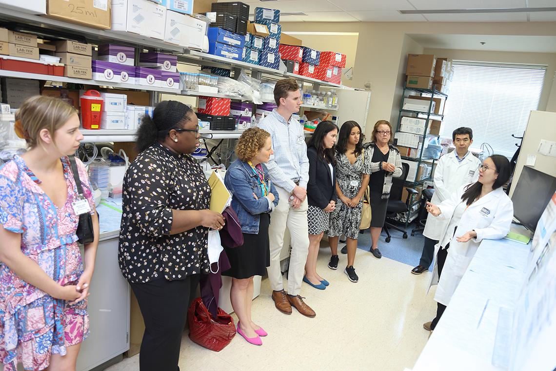 Doctors in white coats speak to staff members in a lab