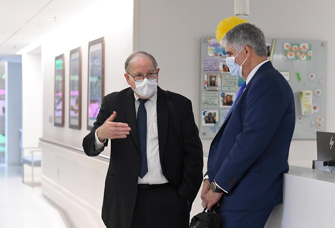 Tabak and Jensen, masked, chat in a hallway