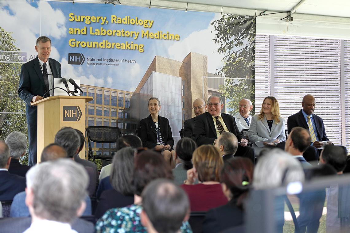 Wheeland speaks on stage. Other members of leadership look on